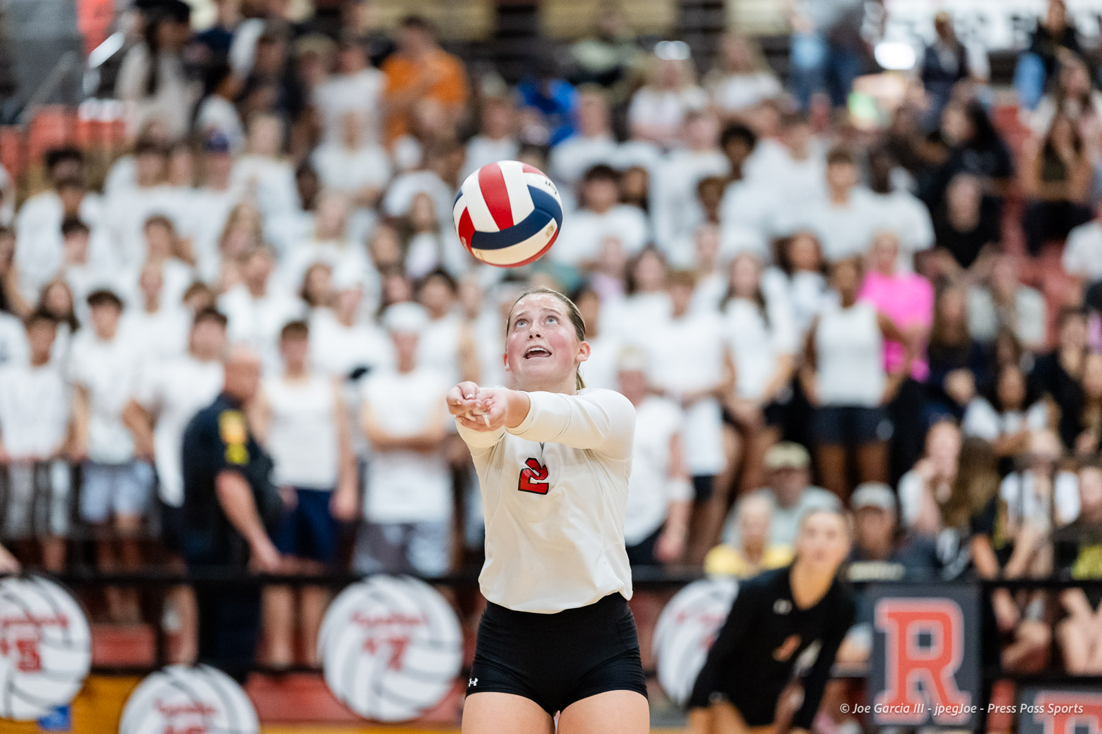 amarillo-high-vs-tascosa-volleyball-jpegJoe-pps-22 | Press Pass Sports Female volleyball player in a white jersey (number 2) serves the ball during a match, with a cheering crowd in white shirts in the background.