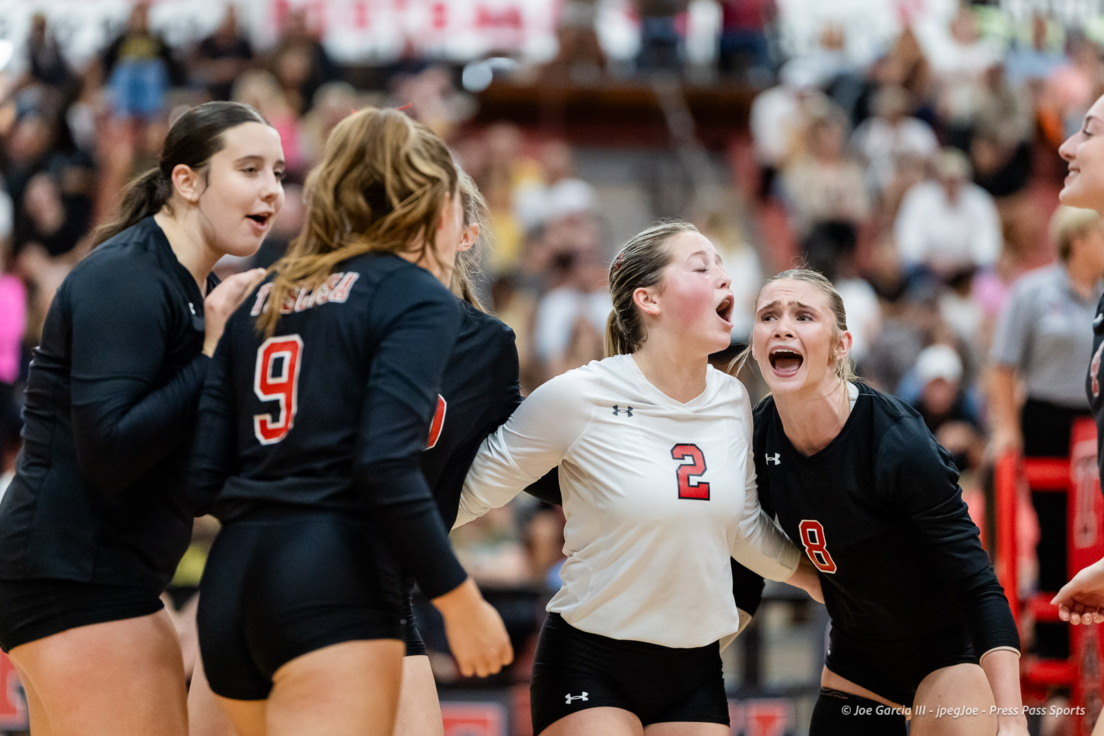 amarillo-high-vs-tascosa-volleyball-jpegJoe-pps-23 | Press Pass Sports Volleyball players in black and white uniforms huddle and cheer on the court during a match, mouths open in celebration or encouragement.