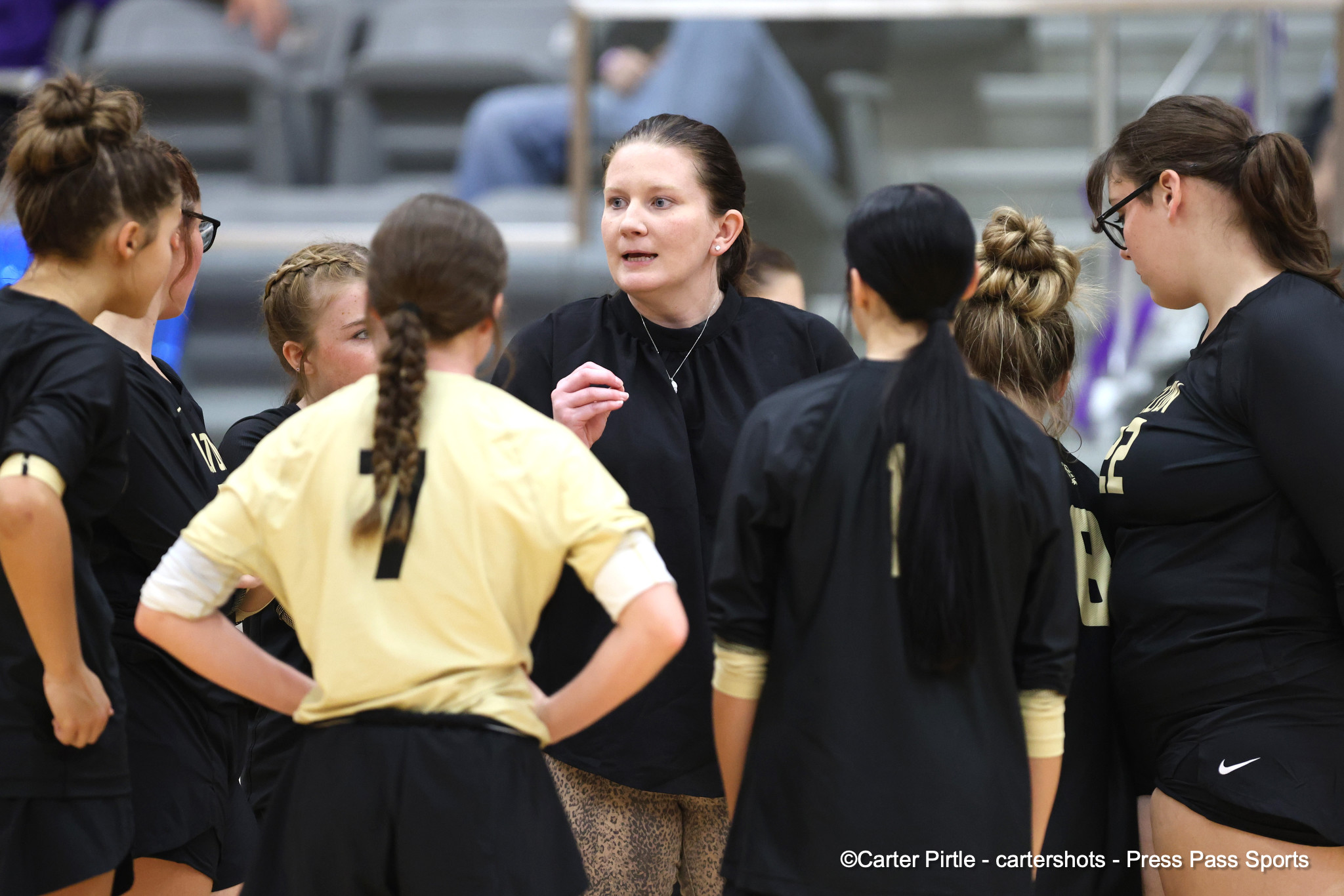 Coach addressing a female sports team in a gym during a huddle?