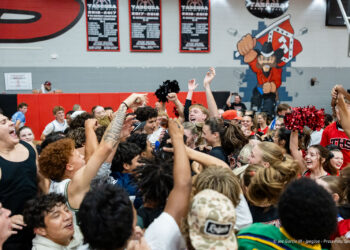 amarillo-high-vs-tascosa-volleyball-jpegJoe-pps-26 | Press Pass Sports Crowd of students cheering and raising hands in a gym during a pep rally, with red wall padding and banners in the background.