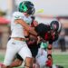 Seabolt Chase-17042 | Press Pass Sports Two football players collide on the field: a ball carrier in a white jersey is tackle‑driven by a defender in black and red.