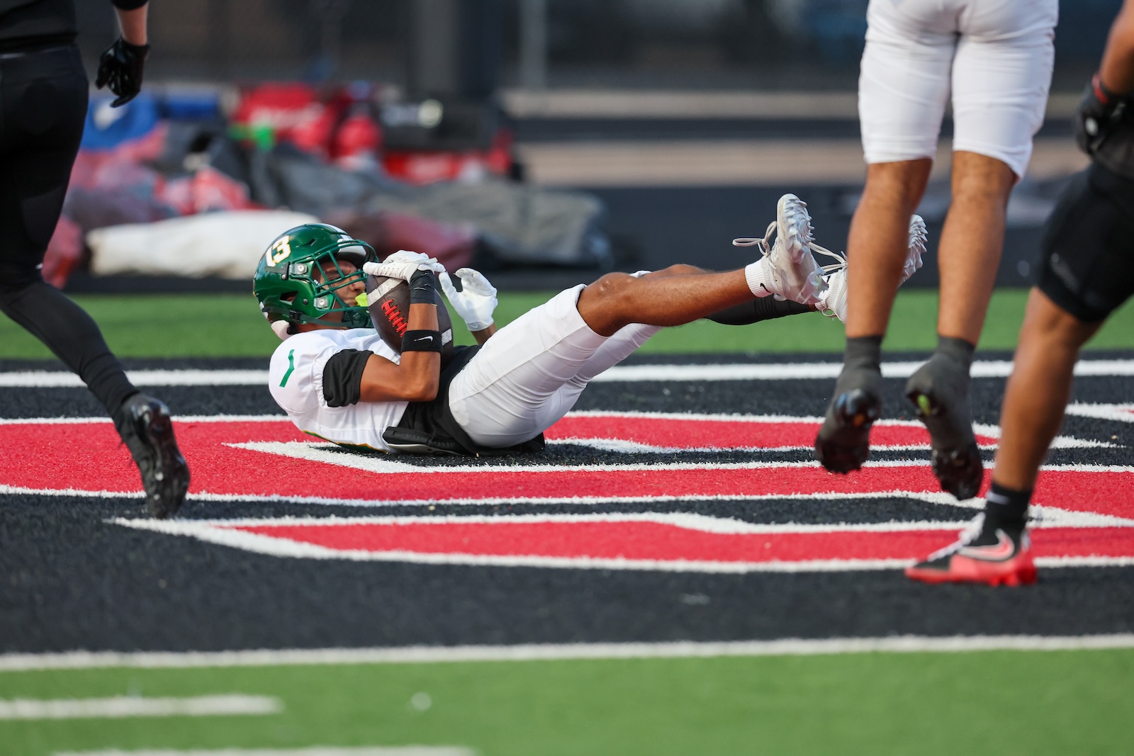 Seabolt Chase-17393 | Press Pass Sports Football player in white dives on artificial turf trying to catch a pass while teammates and opponents approach nearby in a game scene on a red-end zone field line.