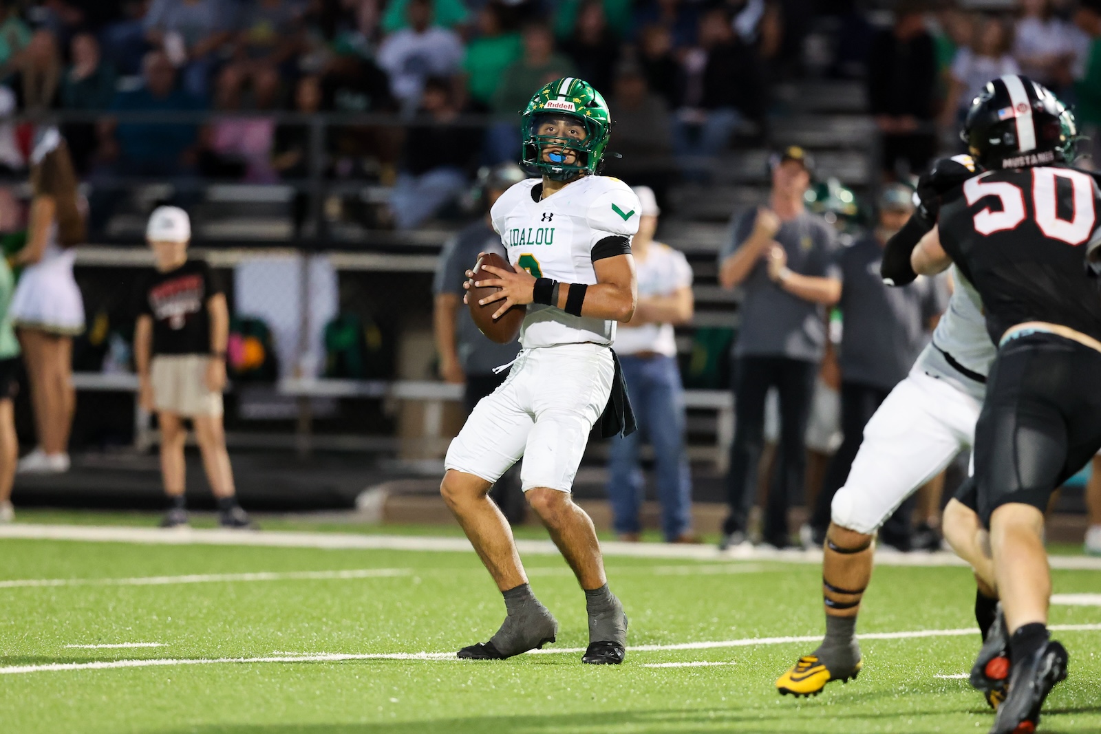 Seabolt Chase-17996 | Press Pass Sports Quarterback in white and green uniform holding a football, looking downfield during a game on a bright turf field