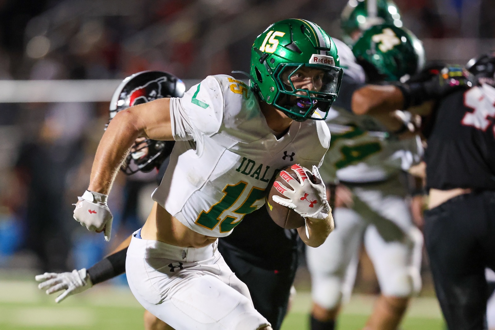 Seabolt Chase-18869 | Press Pass Sports Football player in a white jersey with green number 15, running with the ball during a game, green helmet and white gloves visible.