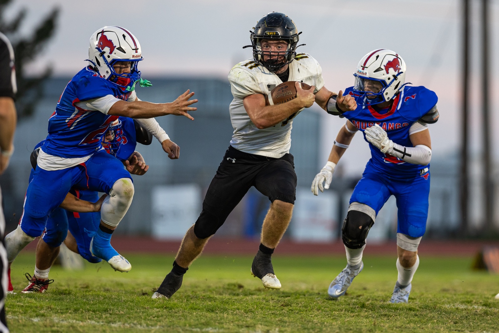 Liberty_15-28 | Press Pass Sports A football player in a white jersey runs with the ball while two defenders in blue uniforms chase him.