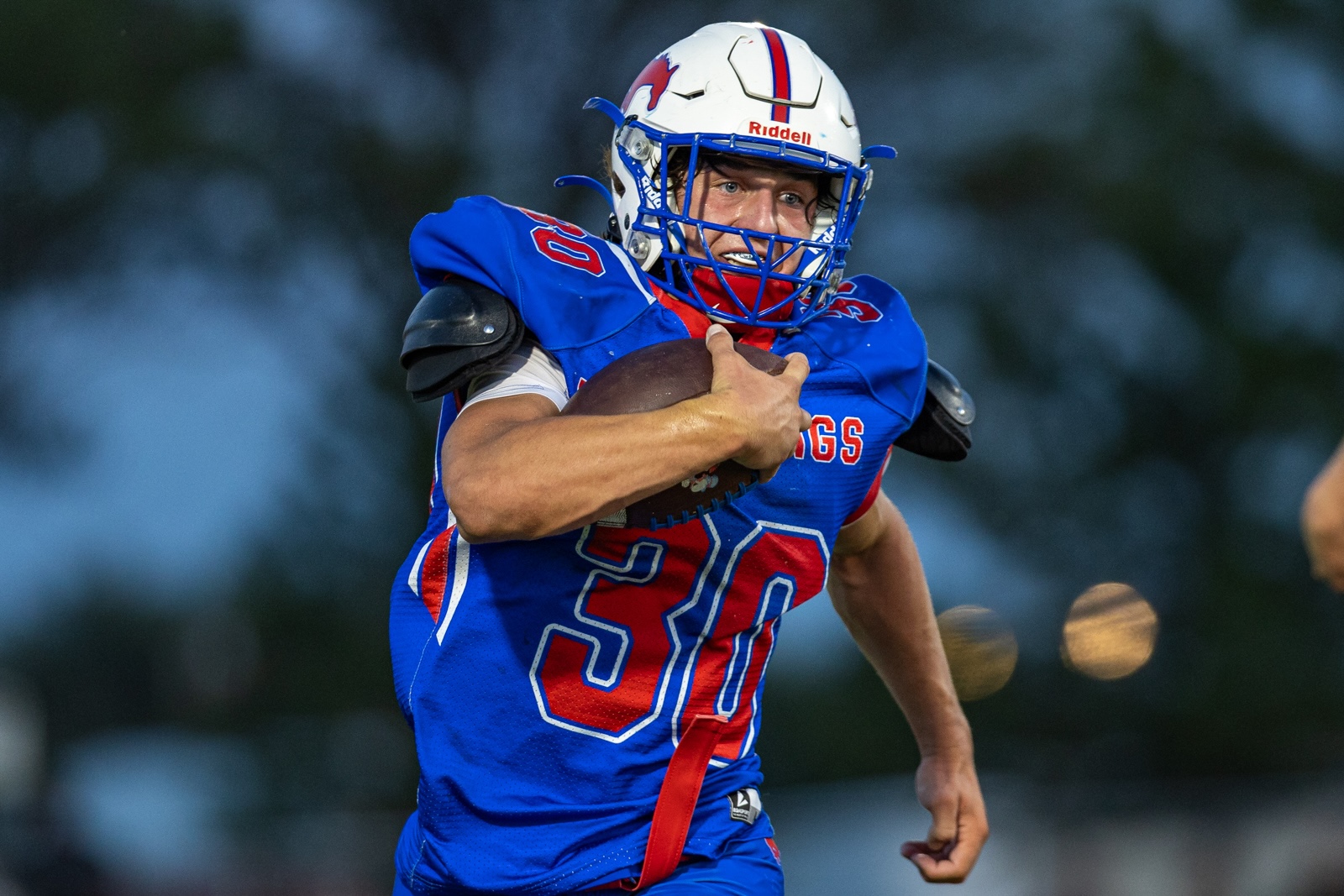 Liberty_15-31 | Press Pass Sports American football player in blue jersey (#33) running with the ball tucked under his arm.