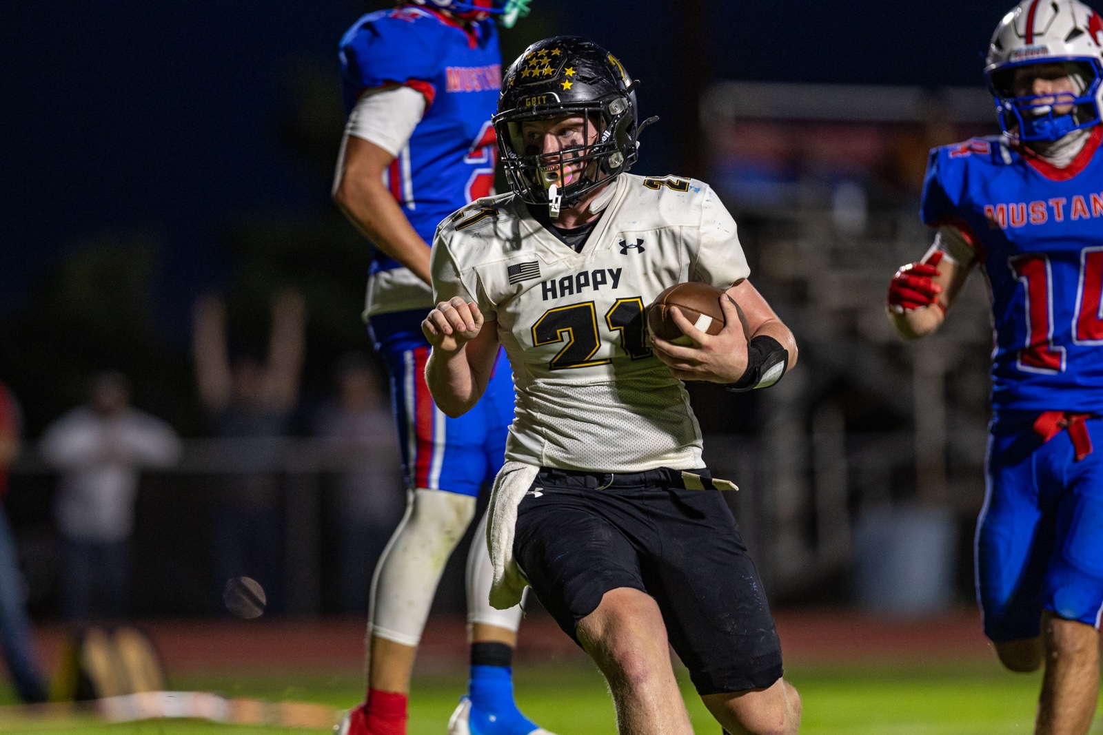 Liberty_15-38 | Press Pass Sports Football player in a white uniform (number 21) runs with the ball during a night game, with blue