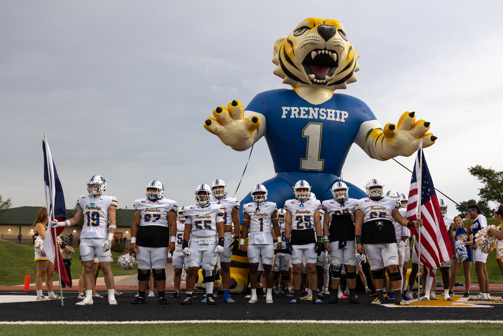 007A5619 | Press Pass Sports Football team in white and blue uniforms stands on track in front of a large blue tiger inflatable mascot holding out its paws.