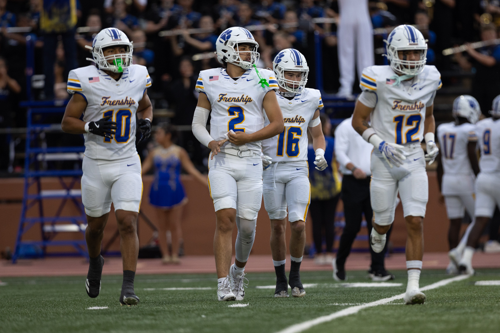 012A5192 | Press Pass Sports Four Frenship football players in white jerseys walk together on the field after a play.