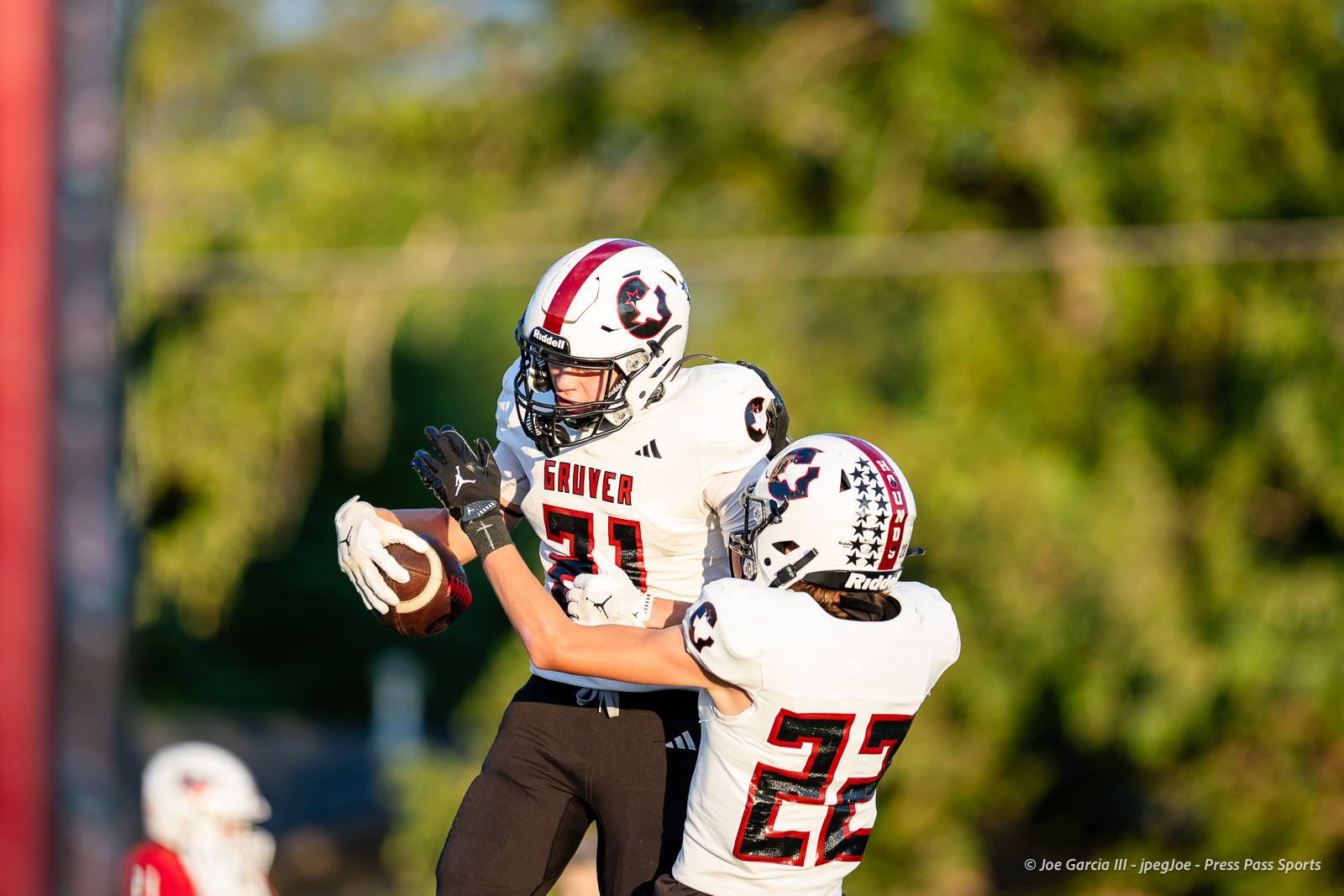gruver-vs-wellinton-2026-jpegJoe-pps-4 | Press Pass Sports Two Gruver football players in white uniforms leap for the ball; #31 reaches for the catch while #23 defends nearby.