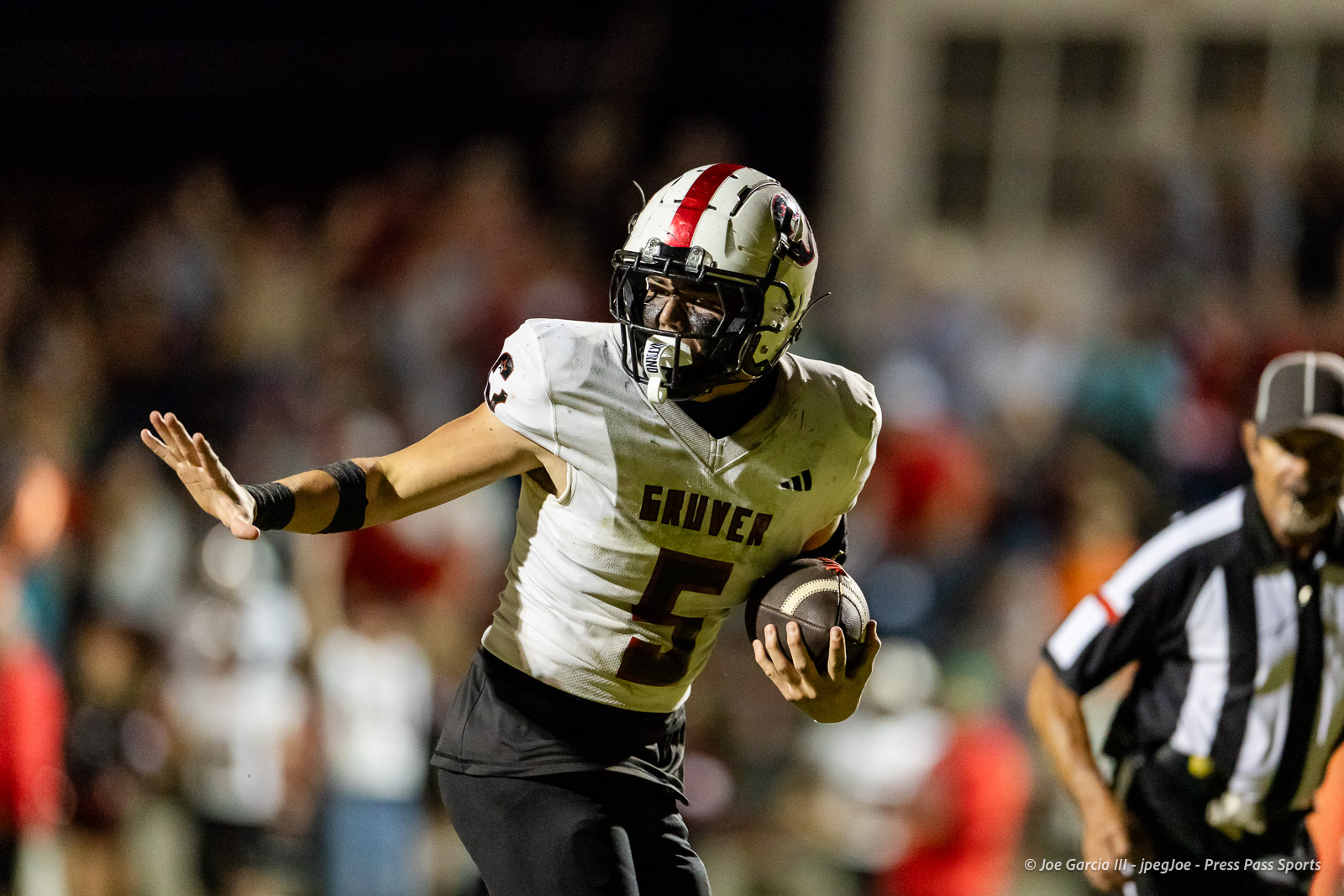 gruver-vs-wellinton-2026-jpegJoe-pps-23 | Press Pass Sports Football player wearing a white Gruver jersey with number 5 runs with the ball during a nighttime game, crowd blurred in the background.