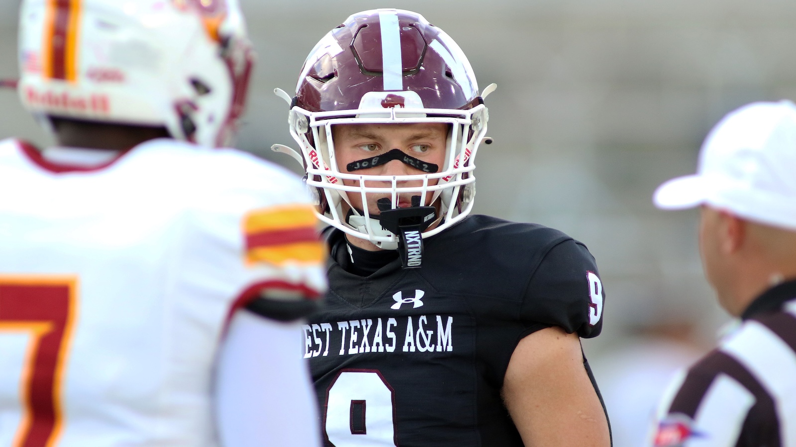 Football player in a West Texas A&M black jersey (#0) and maroon helmet during practice, looking toward teammates.