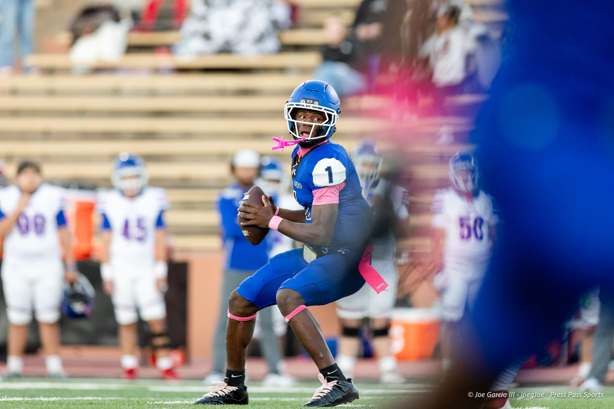abilene-cooper-vs-palo-duro-jpegJoe-pps-4 | Press Pass Sports Football player in blue uniform with the ball, sprinting on a field as blurred teammates and spectators watch in the background.