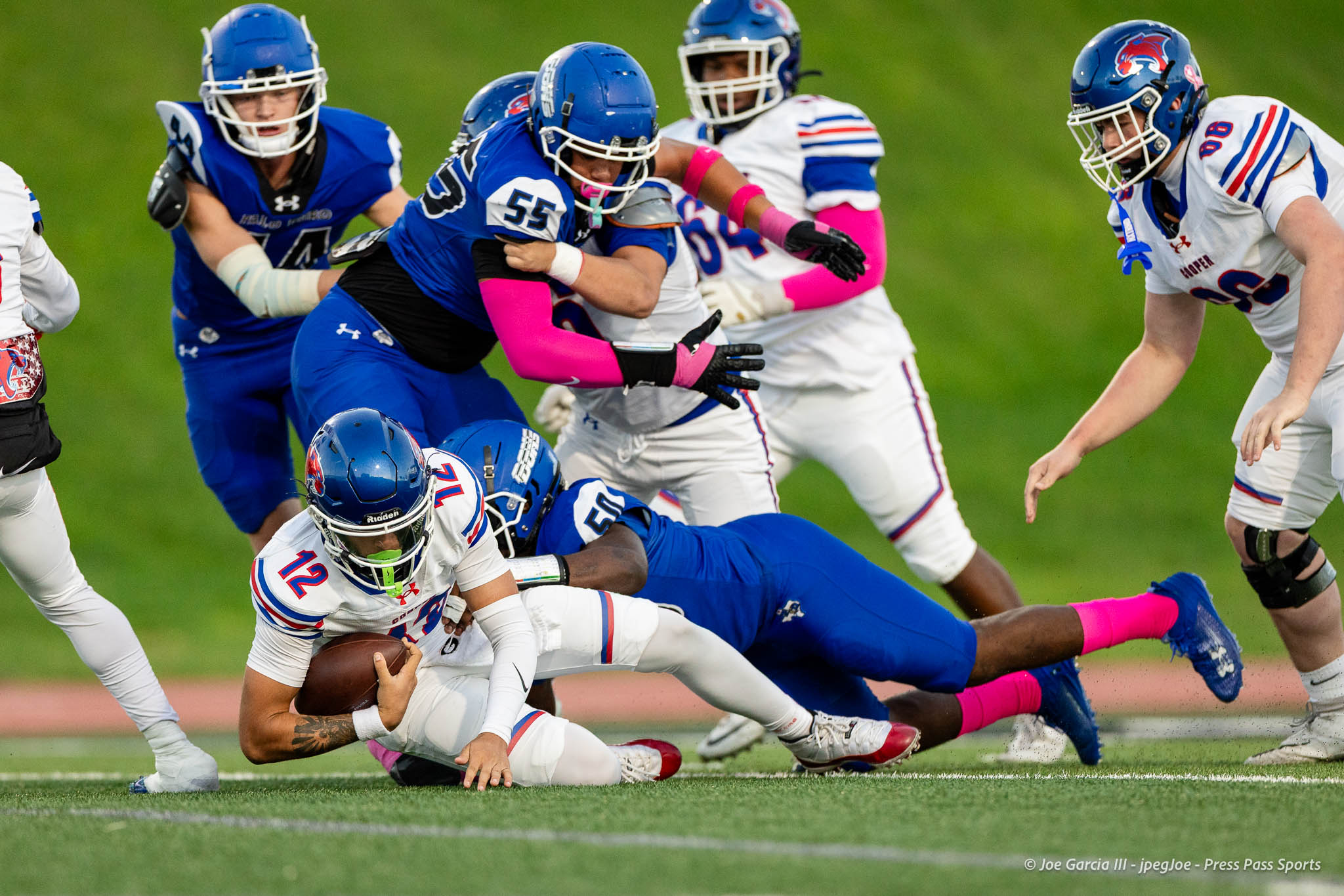 abilene-cooper-vs-palo-duro-jpegJoe-pps-6 | Press Pass Sports Players collide during a football tackle on a grass field; one team in blue, another in white with red/blue accents.