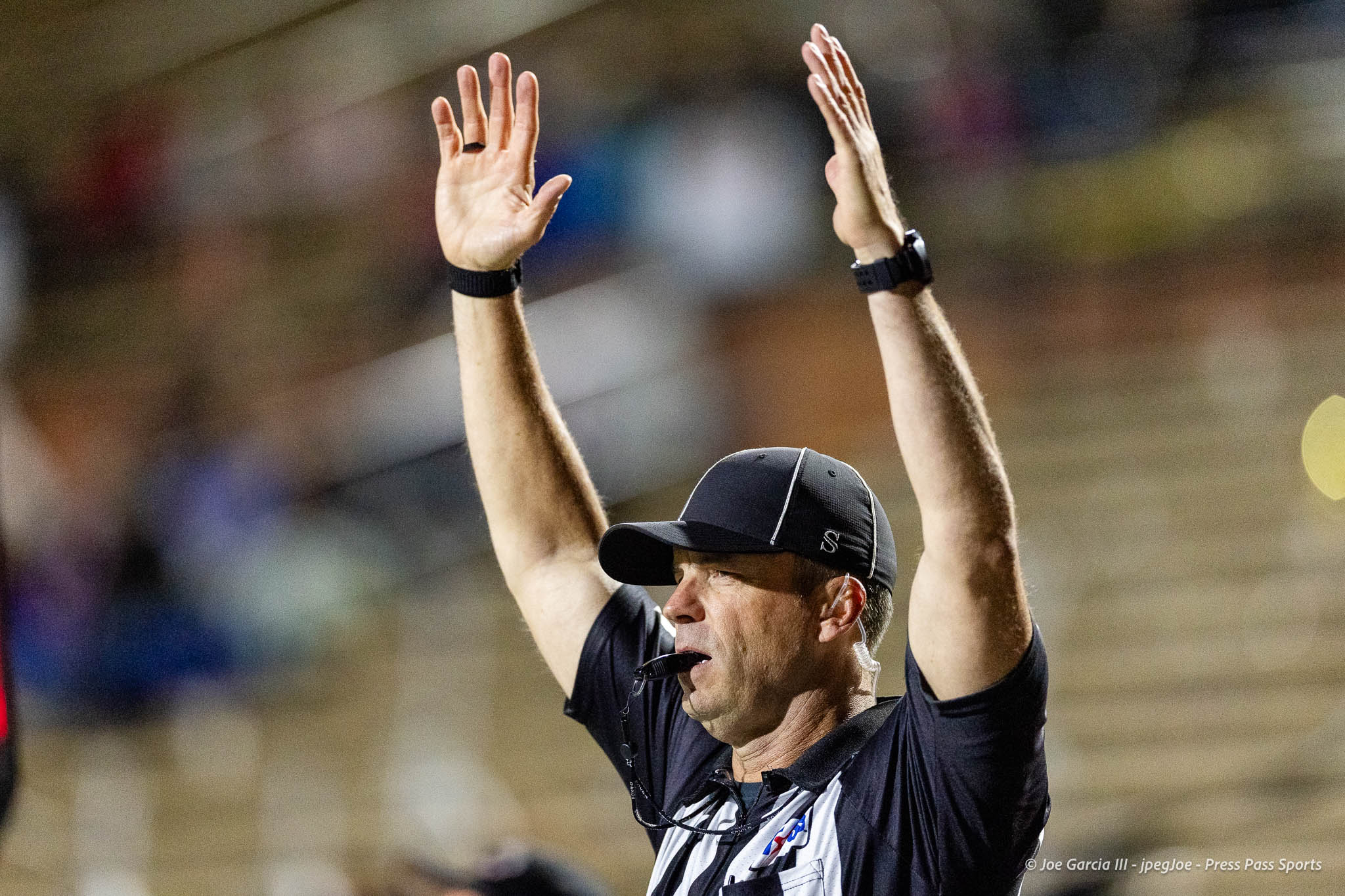 abilene-cooper-vs-palo-duro-jpegJoe-pps-23 | Press Pass Sports Athlete wearing a black cap and dark shirt raises both arms in celebration on a blurred stadium background.