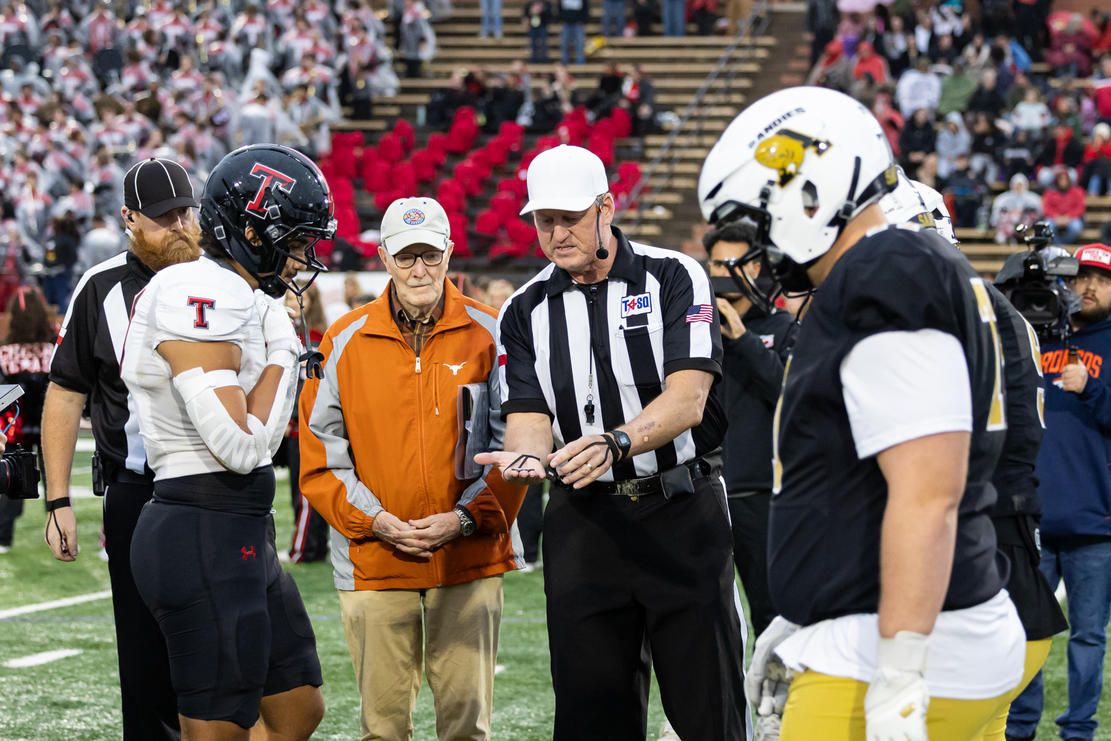 THS-AHS-FB-3 | Press Pass Sports Football game coin toss: referee shows a coin to team captains on the field as players watch nearby.