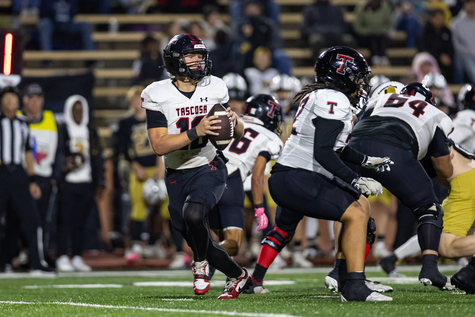 THS-AHS-FB-27 | Press Pass Sports Quarterback in a white Tascosa jersey holds the football and runs forward during a high school football game at night.