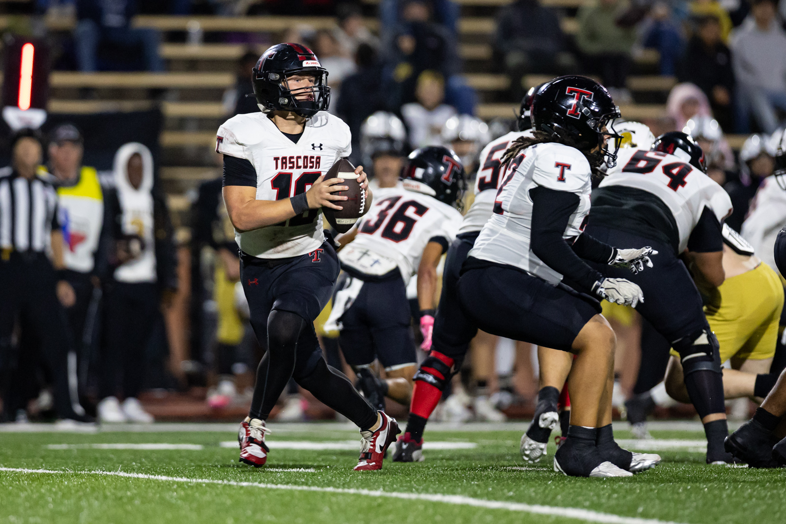 THS-AHS-FB-28 | Press Pass Sports Tascosa quarterback grips the ball and runs, defenders converge on a night football field.