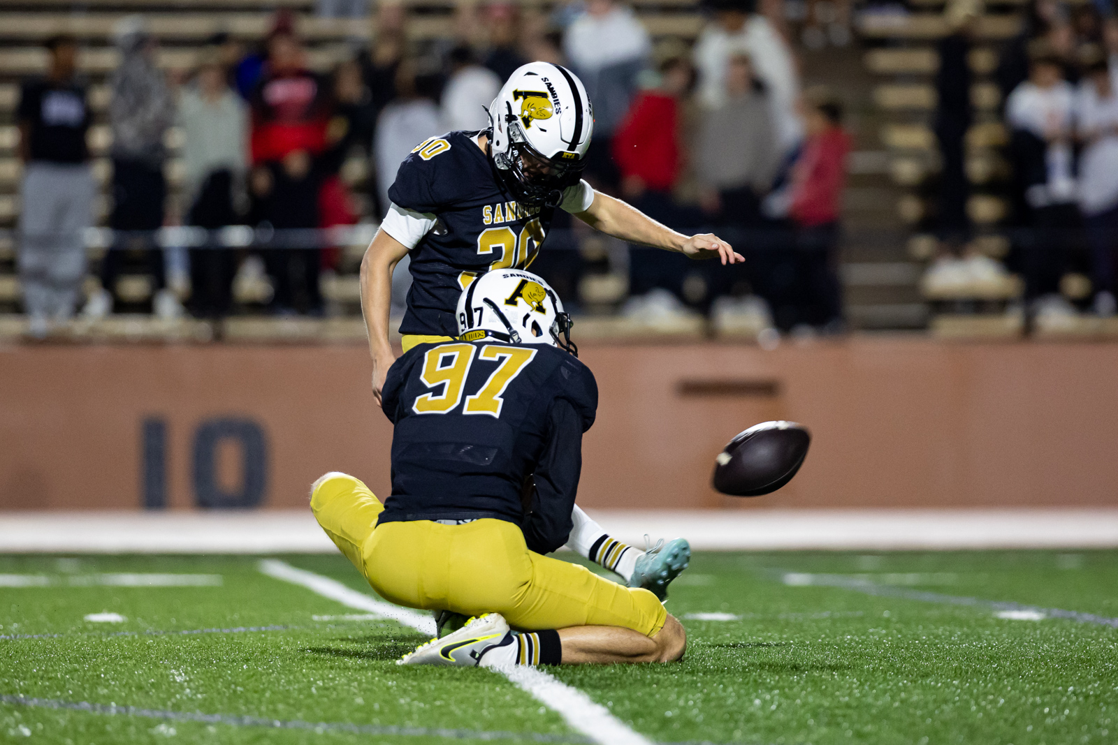 THS-AHS-FB-34 | Press Pass Sports Two football players in Navy and gold collide on a green turf as a football bounces between them and a teammate sits on the ground nearby (numbers 20 and 97 visible).