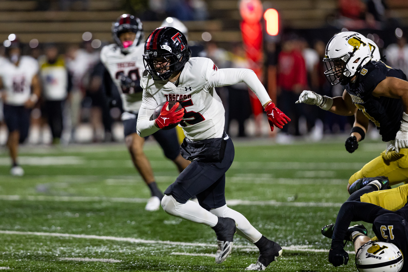 THS-AHS-FB-35 | Press Pass Sports Football player in a white jersey carries the ball and sprints downfield as defenders close in on a green turf field.