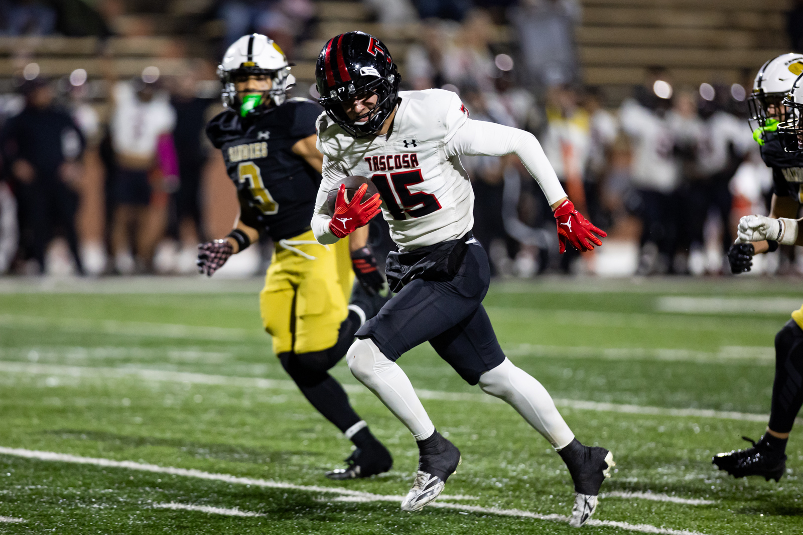 THS-AHS-FB-36 | Press Pass Sports Tascosa player in white #15 running with the football during a night game, pursued by opponents on a green turf field.