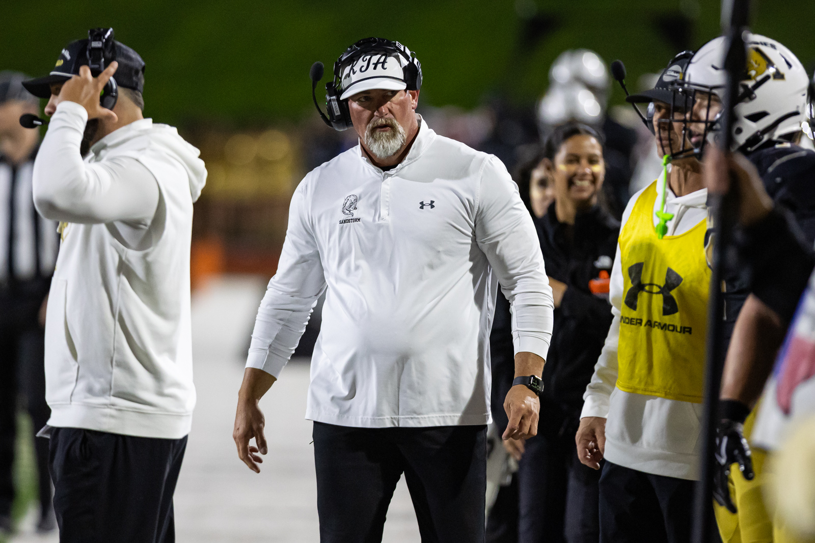 THS-AHS-FB-37 | Press Pass Sports Football coach on the sideline wearing a white polo and headset, gesturing during a game.