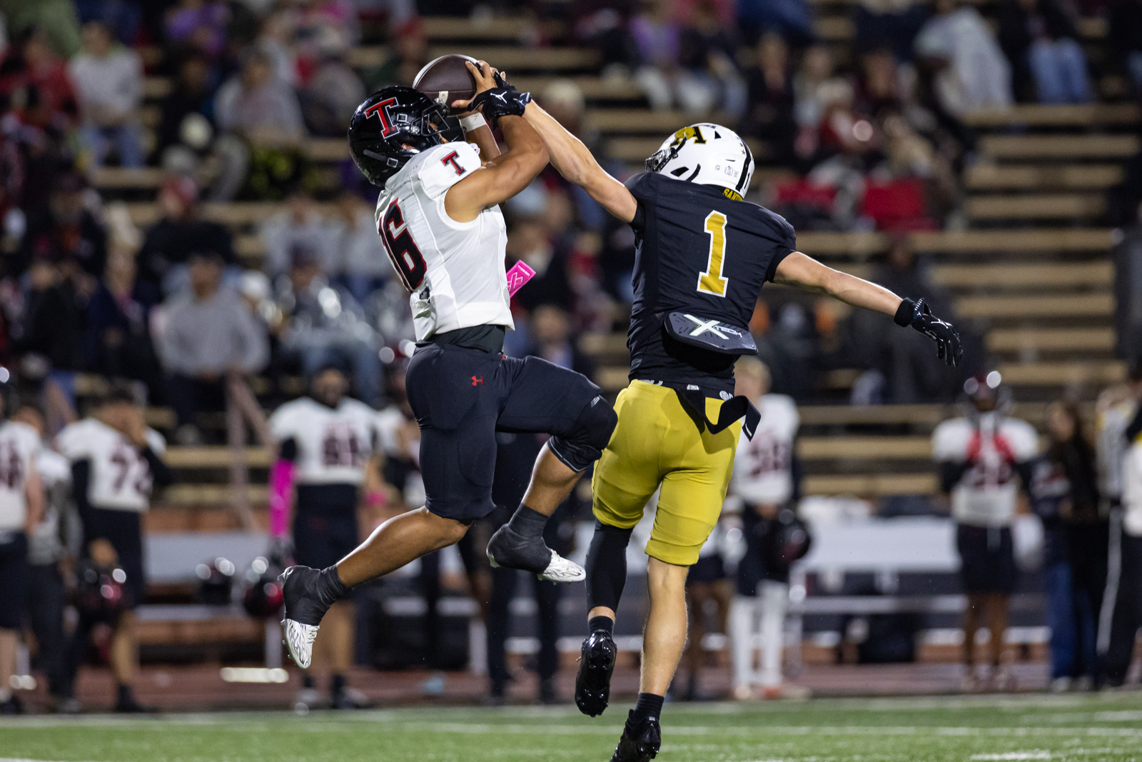 THS-AHS-FB-41 | Press Pass Sports Two football players leap for a catch, colliding mid-air as a crowd watches in a stadium.