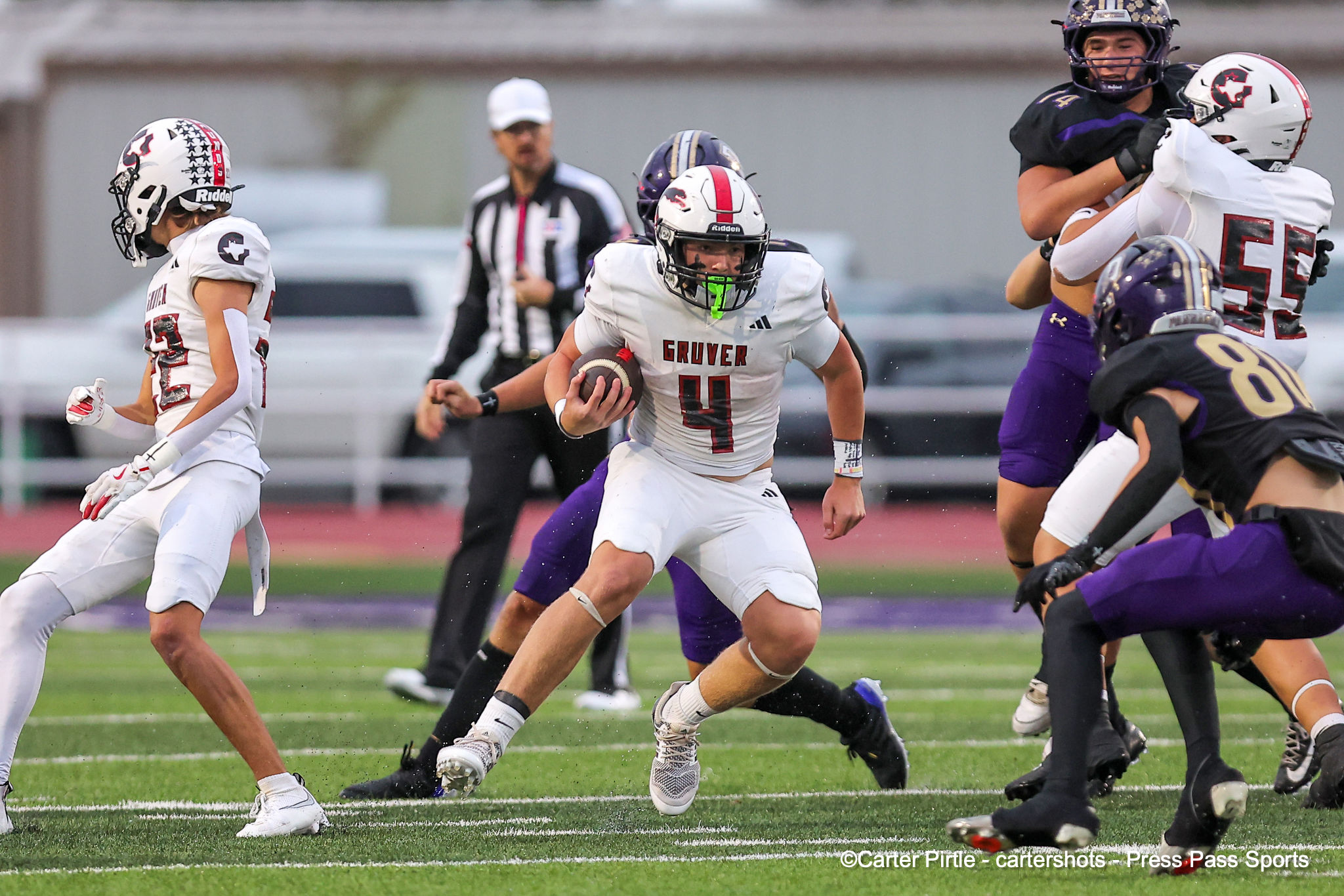 Football action: a Gruver player (number 4) runs with the ball as defenders close in on a green field stadium scene.