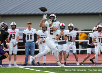 20261002-Gruver-Panhandle-FB-007 | Press Pass Sports Football game: player in white jersey leaping to catch a pass while defenders and teammates watch on the sideline behind him.