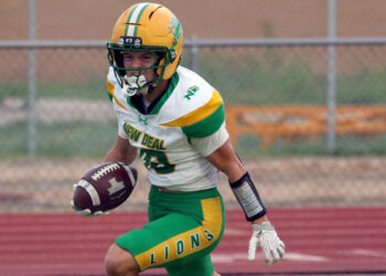 100326 - New Deal vs Sunray - Jacobi Creek | Press Pass Sports Football player in green and gold uniform runs with the ball on a track field ground surface in action.