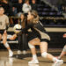 3Q6A3575 | Press Pass Sports Female volleyball players in beige and black uniforms sprint toward the ball on an indoor court as the player in front prepares to pass.