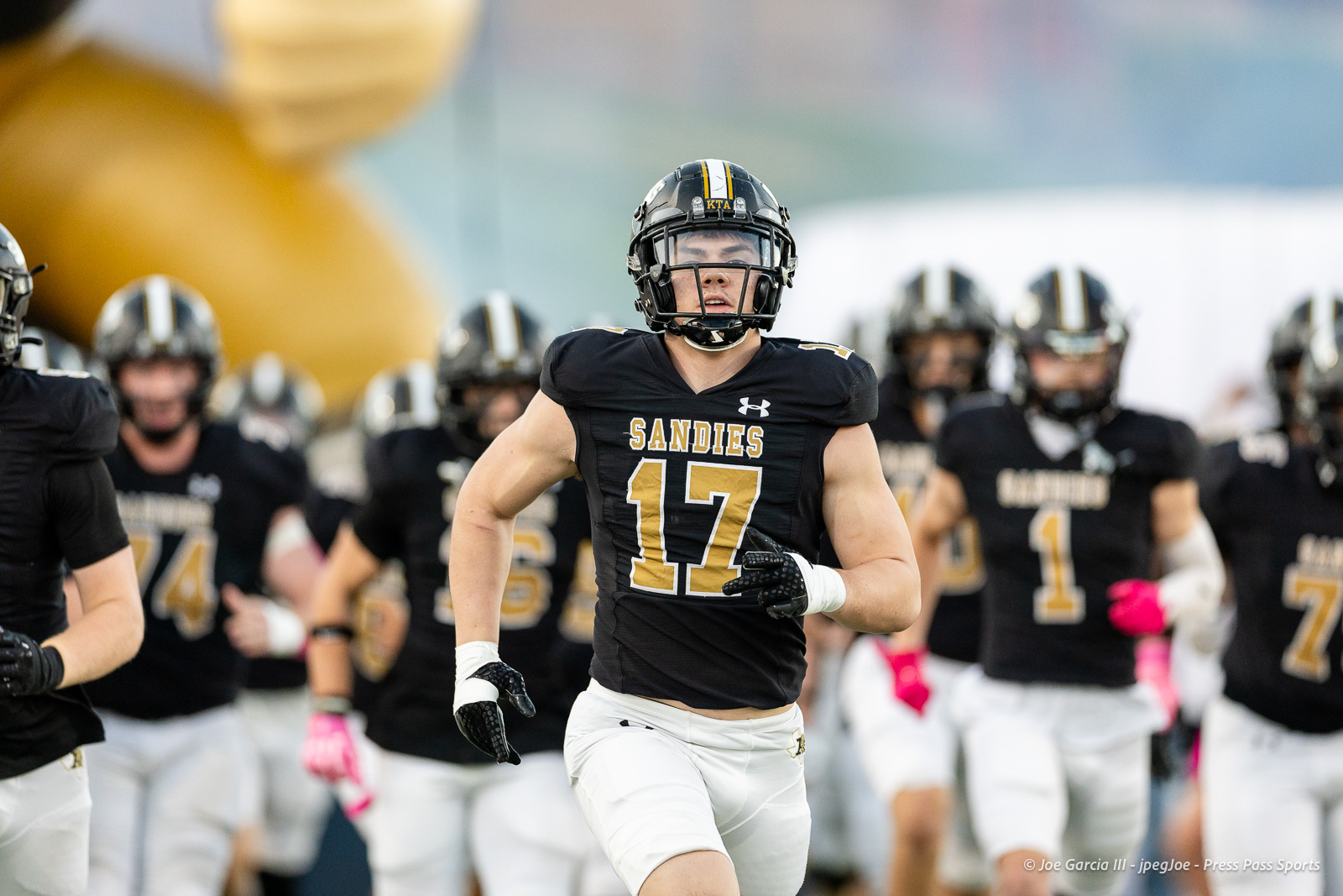 lubbock-monterey-vs-amarillo-high-football-jpegJoe-pps-3 | Press Pass Sports Sandies football player #17 in a black uniform runs toward the camera with teammates behind him.