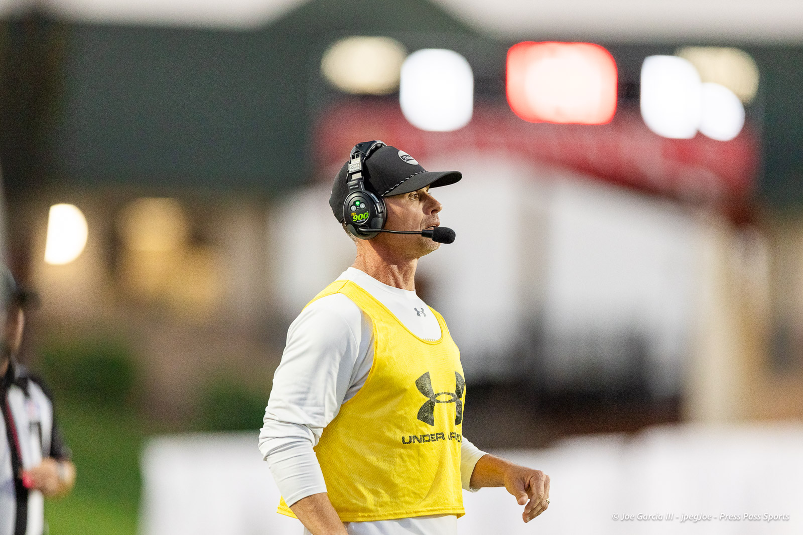 lubbock-monterey-vs-amarillo-high-football-jpegJoe-pps-13 | Press Pass Sports Coach wearing a yellow vest and headset microphone at a sports event.