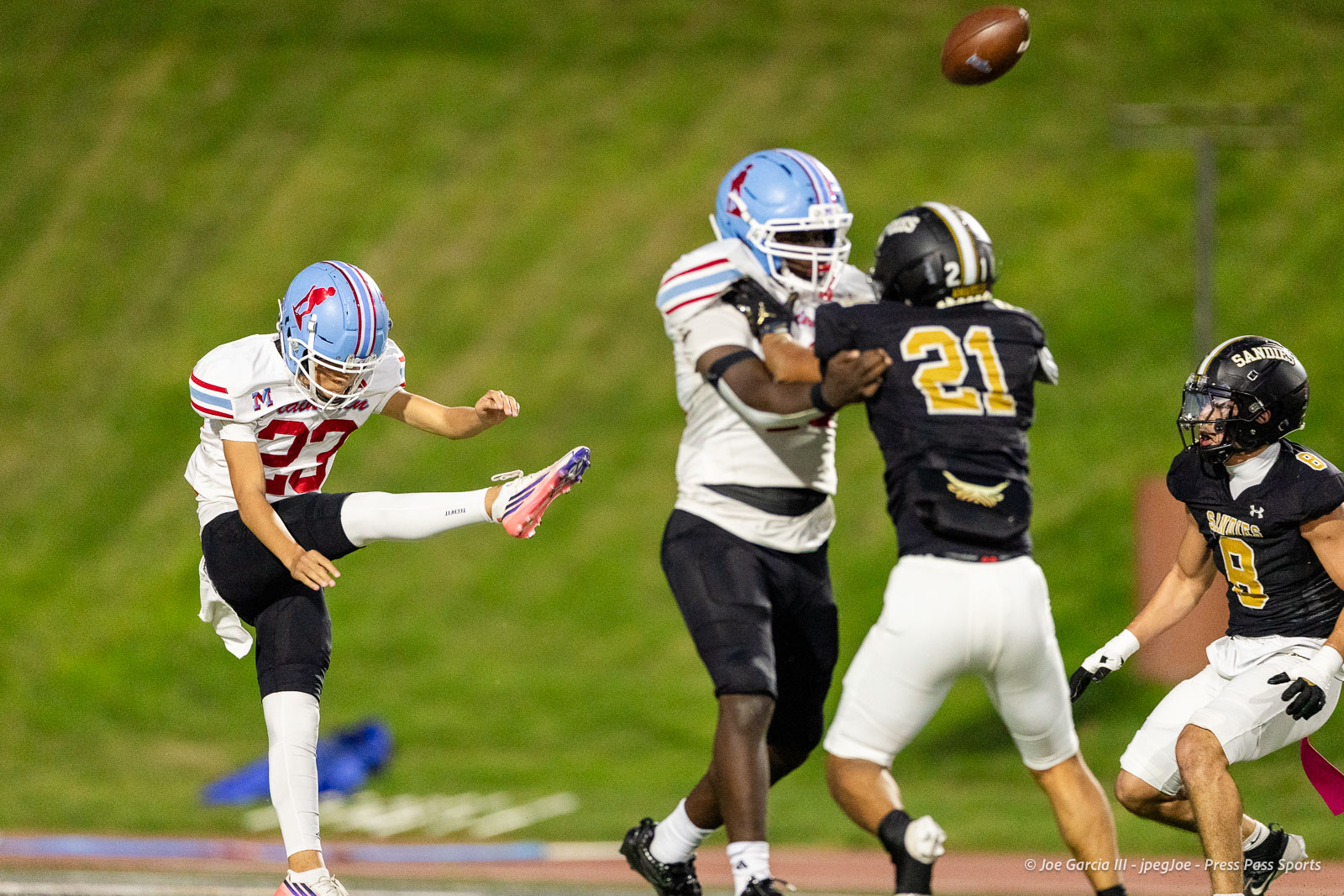 lubbock-monterey-vs-amarillo-high-football-jpegJoe-pps-15 | Press Pass Sports Football players in a kickoff: a white-jersey player with blue helmet kicks the ball while defenders in black jerseys approach across a green field.