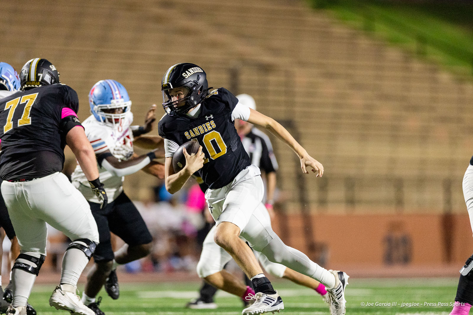 lubbock-monterey-vs-amarillo-high-football-jpegJoe-pps-18 | Press Pass Sports Sandies football player with the ball sprinting past defenders on a night game field in a black jersey number 0.