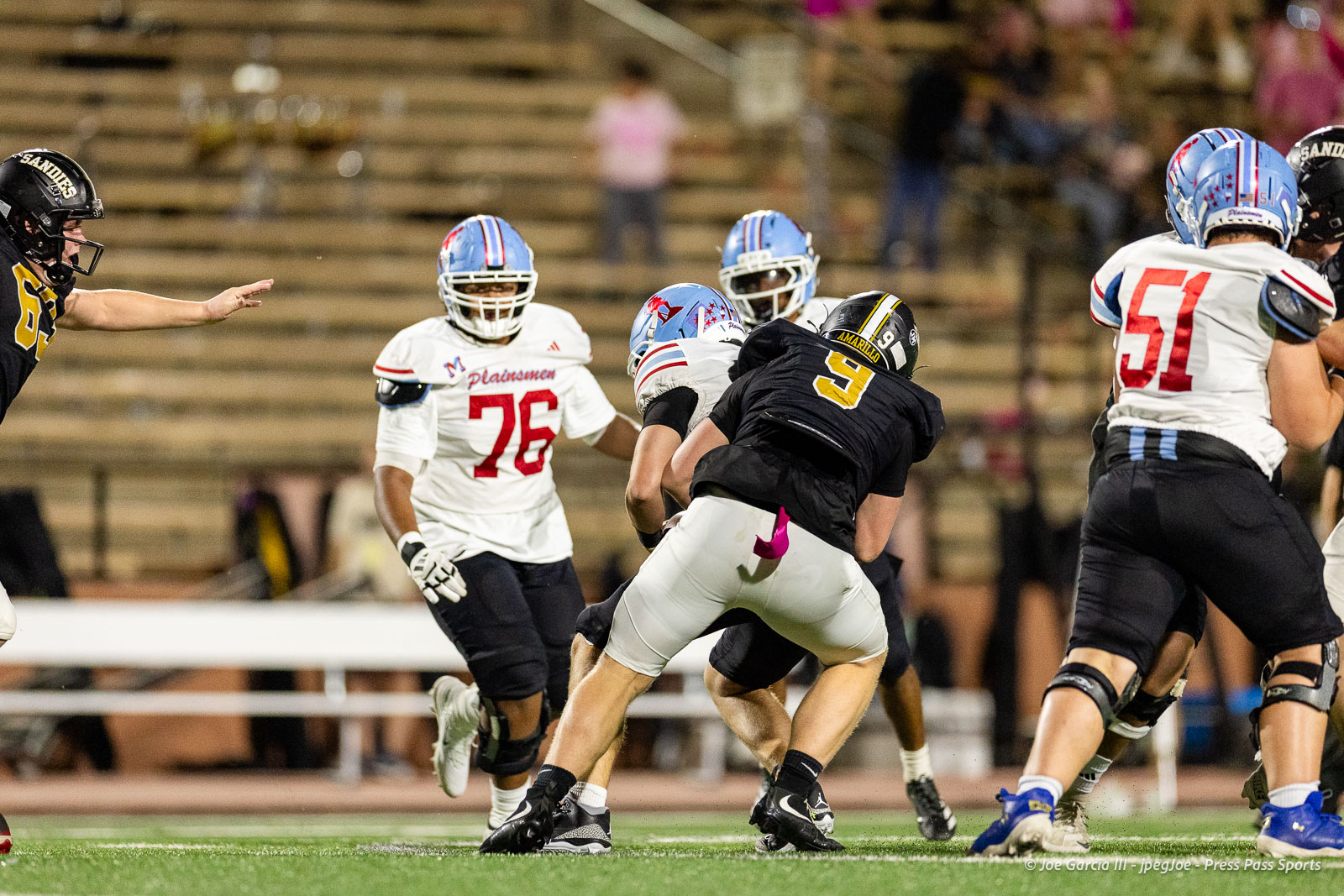 lubbock-monterey-vs-amarillo-high-football-jpegJoe-pps-20 | Press Pass Sports Action shot of a football game with players in white and black jerseys colliding on the field amidst a crowd in the stands.