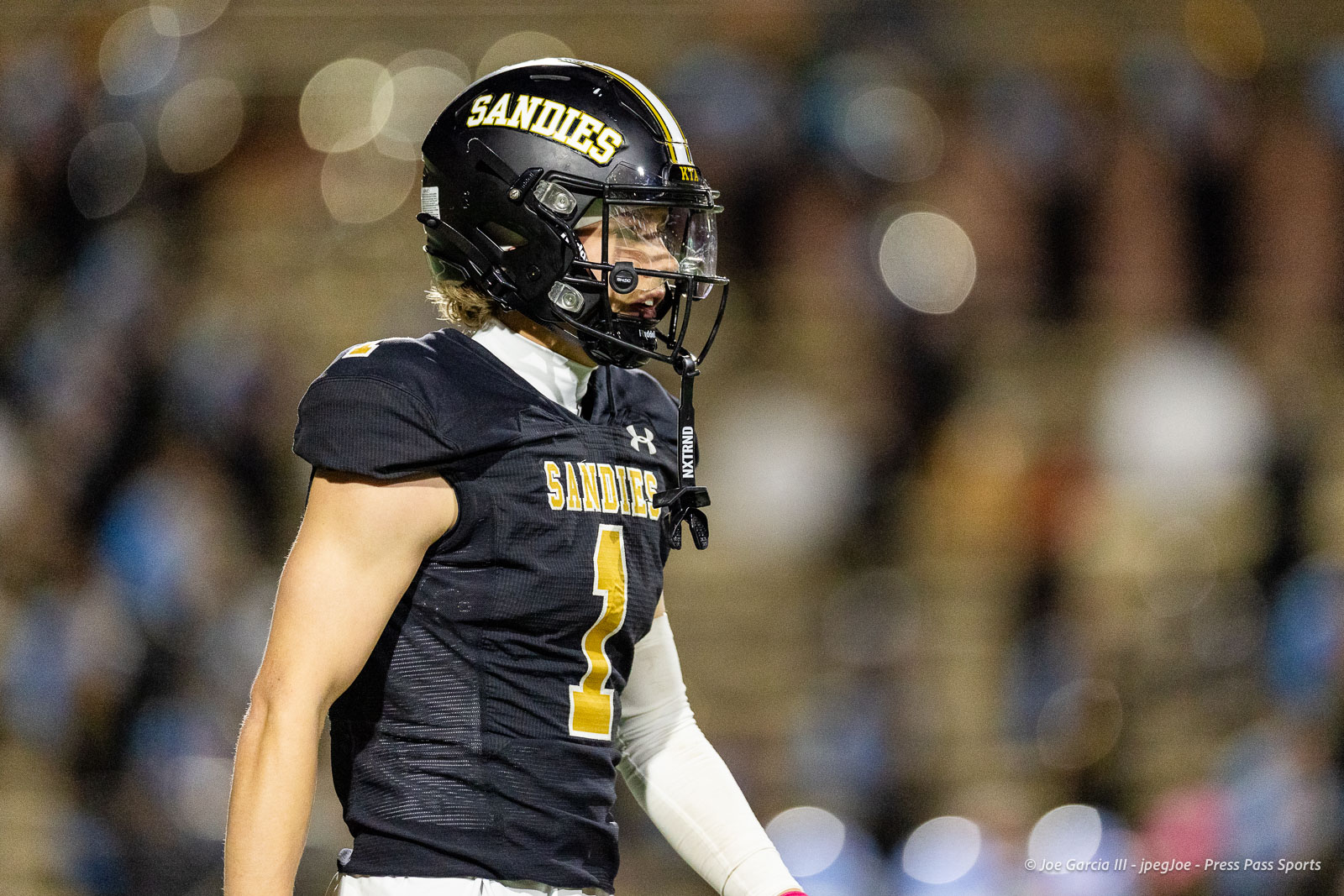 lubbock-monterey-vs-amarillo-high-football-jpegJoe-pps-23 | Press Pass Sports American football player in a black Sandies jersey (#1) wearing a helmet, on the field with a blurred crowd in the background.