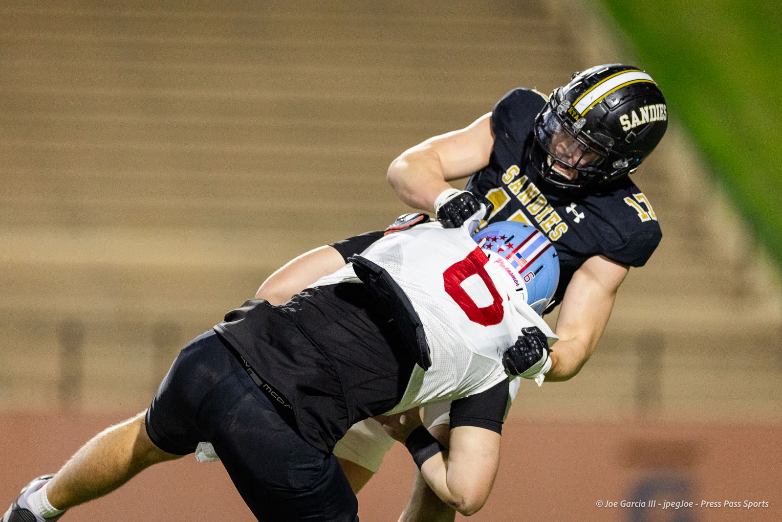lubbock-monterey-vs-amarillo-high-football-jpegJoe-pps-25 | Press Pass Sports Two football players collide: a Sandies in black jersey tackling a white-jersey opponent with a blue helmet during a game.