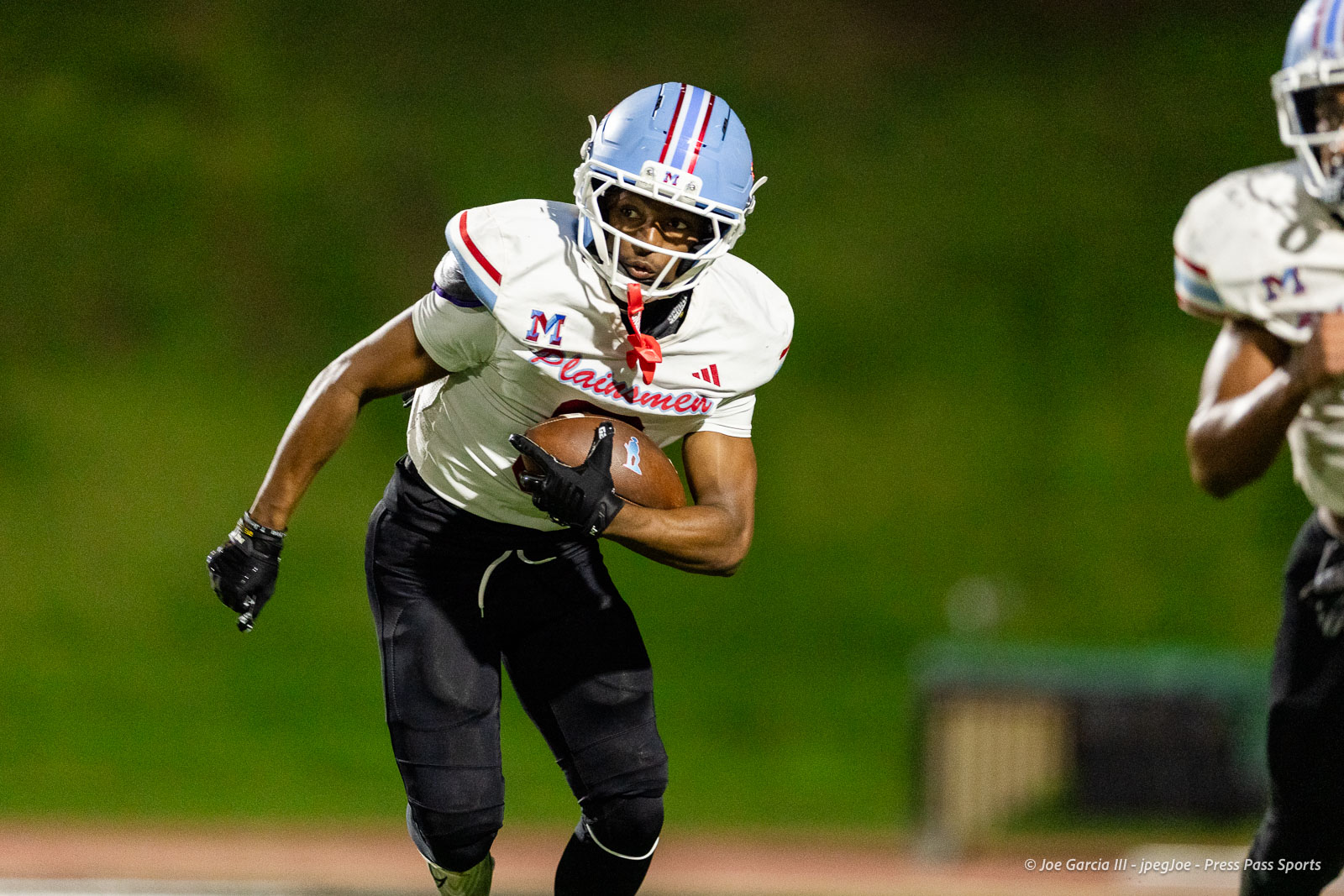lubbock-monterey-vs-amarillo-high-football-jpegJoe-pps-26 | Press Pass Sports Football player in a white jersey holding the ball and running on a field at night, helmet blue with red stripeed decals.