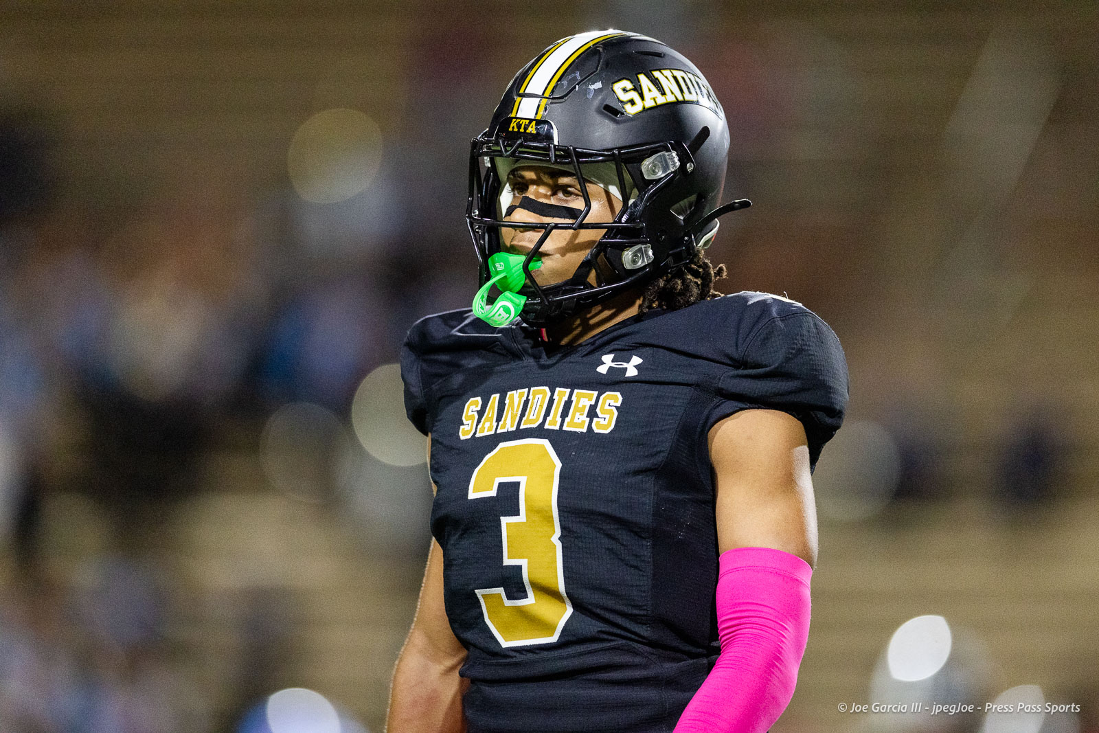 lubbock-monterey-vs-amarillo-high-football-jpegJoe-pps-32 | Press Pass Sports Football player from the Sandies, wearing jersey number 3 and a black helmet, neon pink sleeve on his right arm, on the field with a green mouthguard