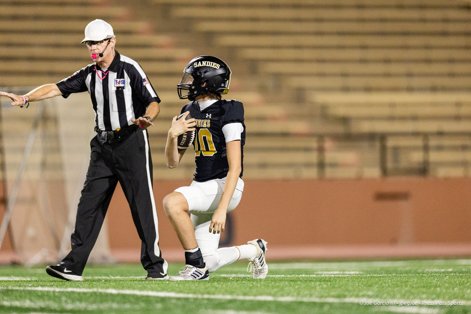 lubbock-monterey-vs-amarillo-high-football-jpegJoe-pps-38 | Press Pass Sports Football player in navy uniform kneels on the field, holding the ball, as the referee signals nearby.