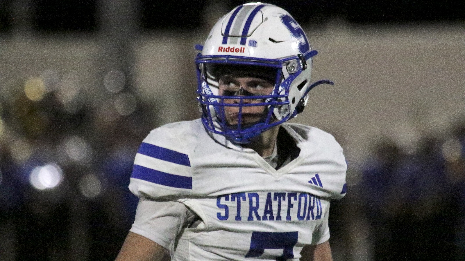 American football player in a white and blue Stratford uniform and helmet, looking to the right on the field.