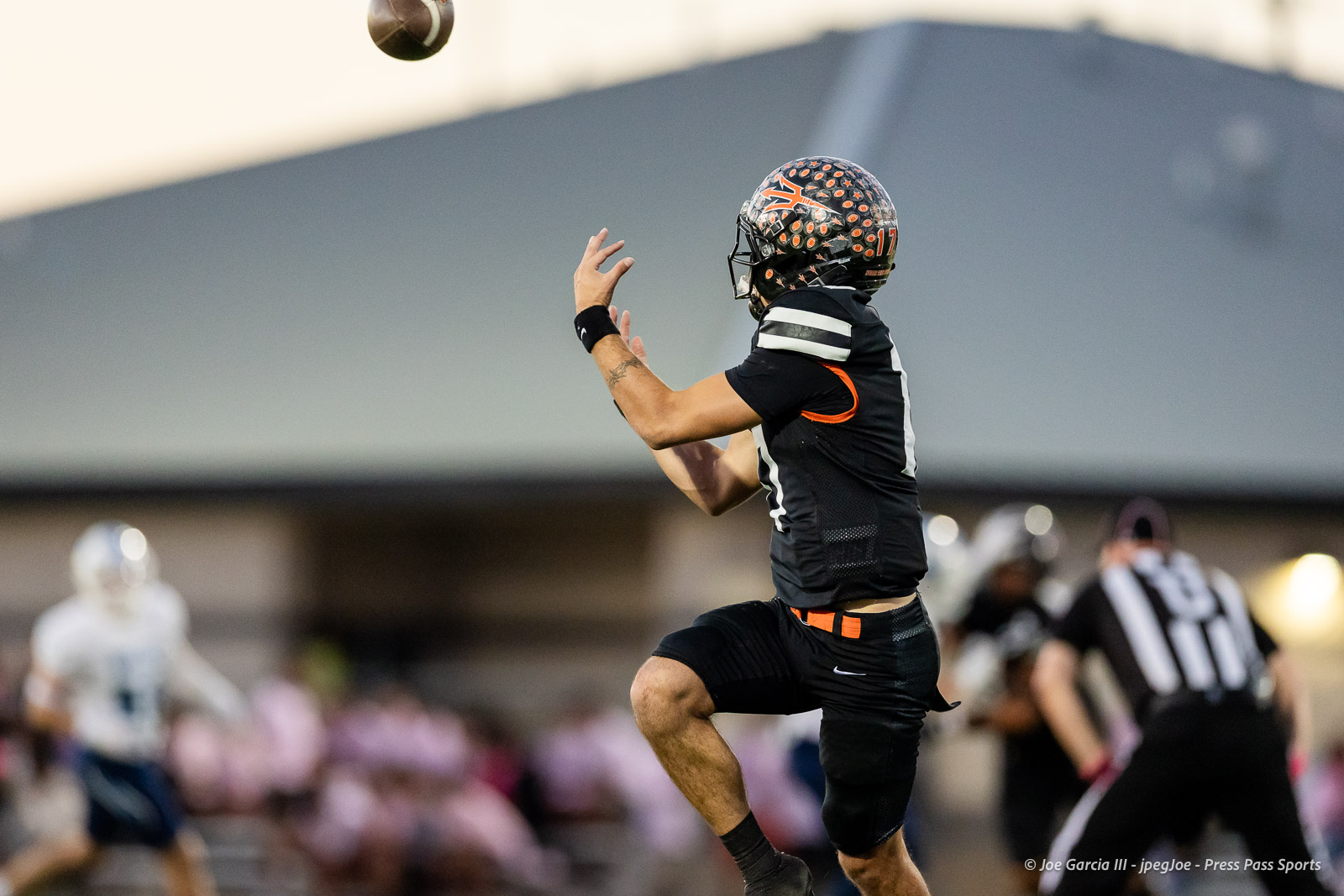 west-plains-vs-dumas-football-jpegJoe-pps-11 | Press Pass Sports Football player in black uniform jumps to catch a pass during a game, ball in midair above him.