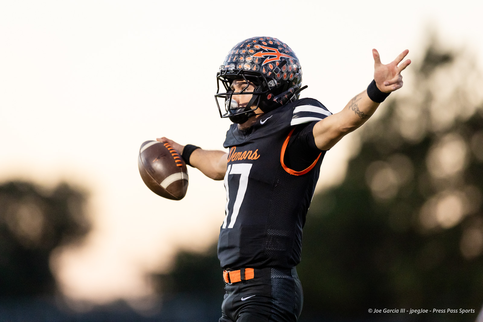 west-plains-vs-dumas-football-jpegJoe-pps-14 | Press Pass Sports Quarterback in a black jersey (number 17) throws a football during a game, wearing a patterned helmet and orange accents.