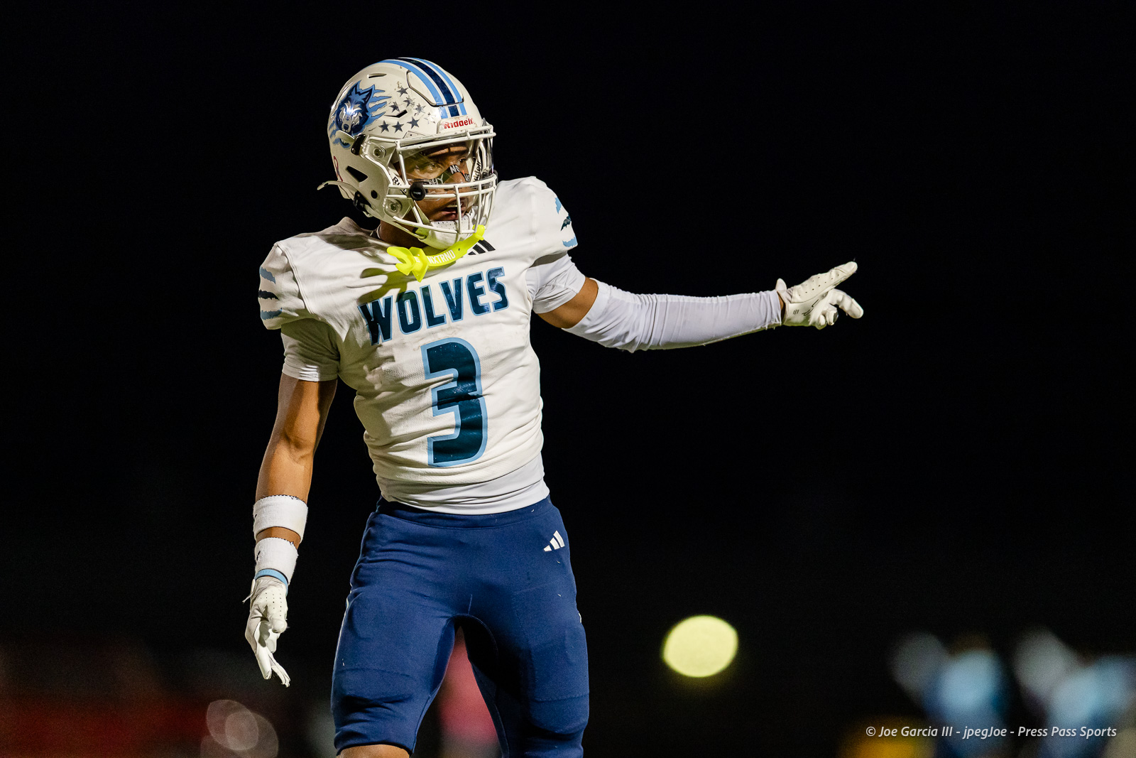 west-plains-vs-dumas-football-jpegJoe-pps-27 | Press Pass Sports Football player in a white Wolves jersey with number 3, wearing a helmet, pointing to the right during a night game.