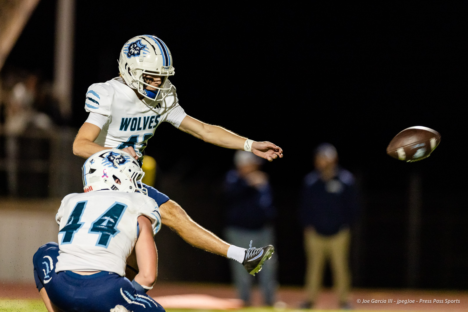 west-plains-vs-dumas-football-jpegJoe-pps-45 | Press Pass Sports Nighttime high school football: Wolves player leaps to punt or pass the ball while another player blocks nearby, ball in midair.