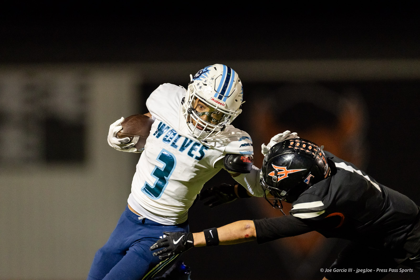 west-plains-vs-dumas-football-jpegJoe-pps-52 | Press Pass Sports Melville football player #3 in white and blue carries the ball while a defender in black tackles him during a night game.