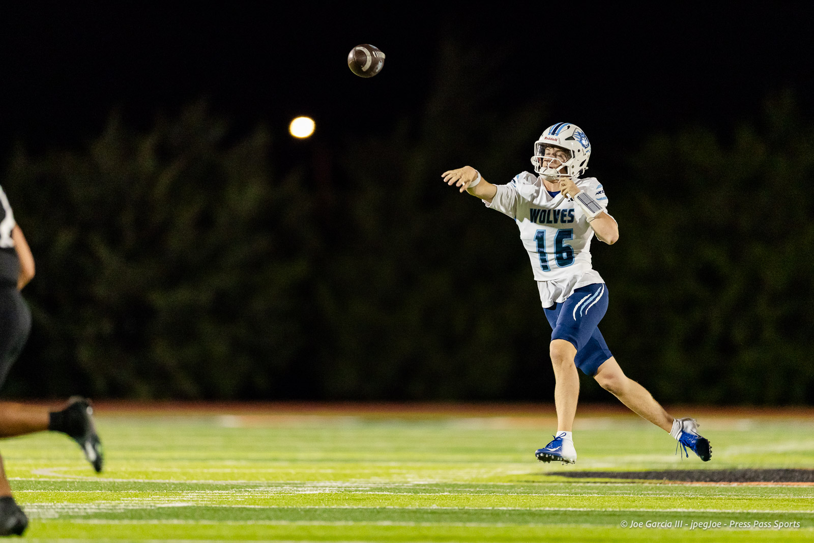 west-plains-vs-dumas-football-jpegJoe-pps-56 | Press Pass Sports Quarterback in a Wolves uniform throwing a football during a night game on a lit field, number 16 visible on the jersey.