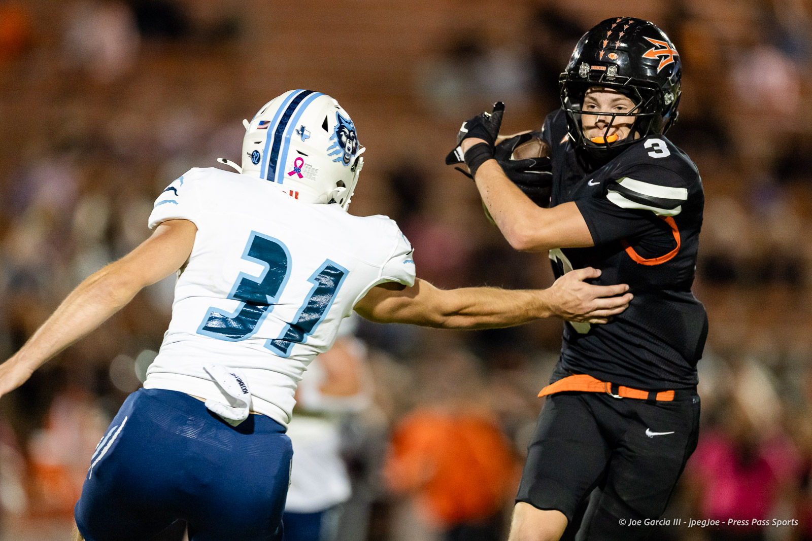 west-plains-vs-dumas-football-jpegJoe-pps-60 | Press Pass Sports Two football players clash on the field: a white‑jerseyed player #21 reaching to tackle a black‑jerseyed player #3 as the crowd looks on.