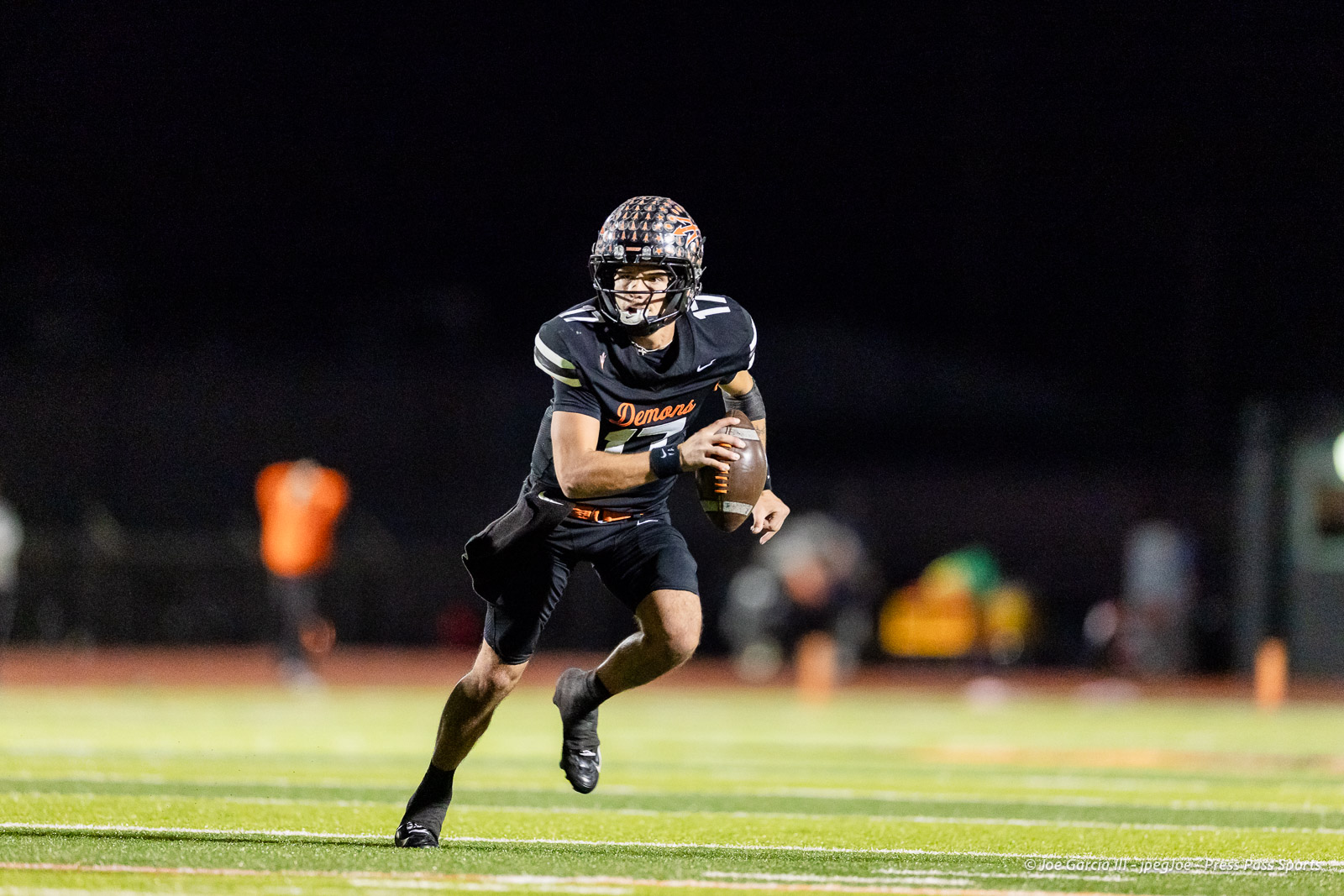 west-plains-vs-dumas-football-jpegJoe-pps-64 | Press Pass Sports Nighttime football action: player in a black Demons jersey runs with the ball on a brightly lit field, helmet on